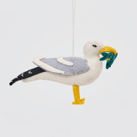 Handmade felt Seagull ornament from Craftspring rotating to show front, side, and back views—highlighting embroidered details and the fish in its beak, sustainably handmade by artisans using wool.