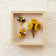 Bee-themed felt shadow box featuring three hand-felted ornaments on cream fabric