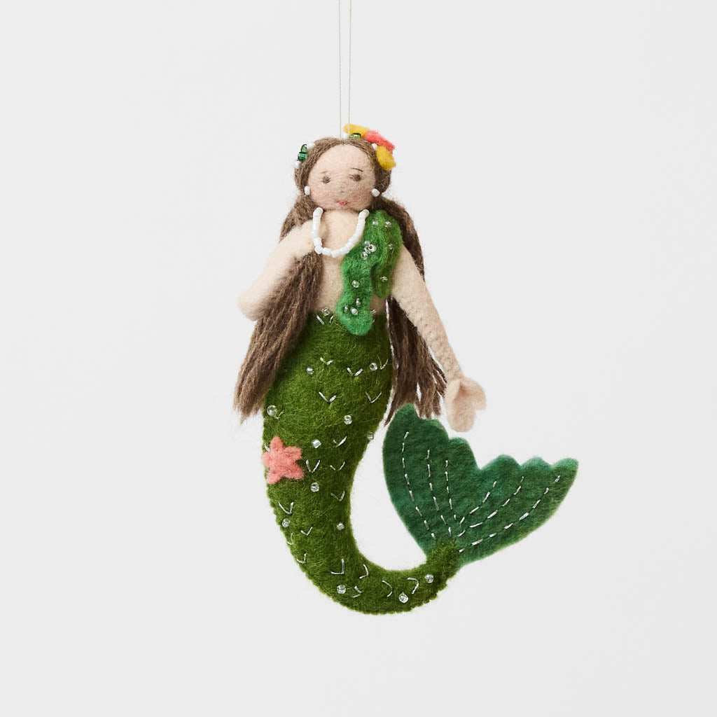 Add a touch of ocean magic to your Christmas tree with our beautiful Siren Mermaid Ornament. Lovingly handcrafted from eco-friendly wool felt, this elegant mermaid features flowing brunette hair, a vibrant green tail adorned with sparkling bead accents, and charming floral details inspired by the treasures of the sea.
