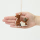 Craftspring’s Sitting Deer with Friends Ornament in front of a hand to show its size—handmade from sustainable wool, featuring a deer with a rabbit, squirrel, and bird, with delicate beaded and embroidered details, ethically crafted by artisans using sustainable wool.