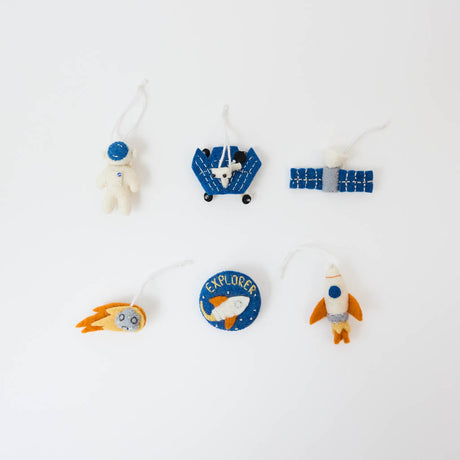 Blast off into a universe of discovery with our Space Mini Ornaments Set. This delightful collection includes five handcrafted felt ornaments inspired by the wonders of space: an astronaut, satellite, space shuttle, rocket ship, and meteor, along with a coordinating Explorer badge that can be displayed as a keepsake or worn as a symbol of curiosity and adventure.