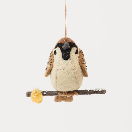 Celebrate the quiet beauty of everyday birds with our Sparrow Ornament. Small yet full of personality, this beloved garden bird is lovingly hand-felted from natural wool and perched on a delicate felt branch.