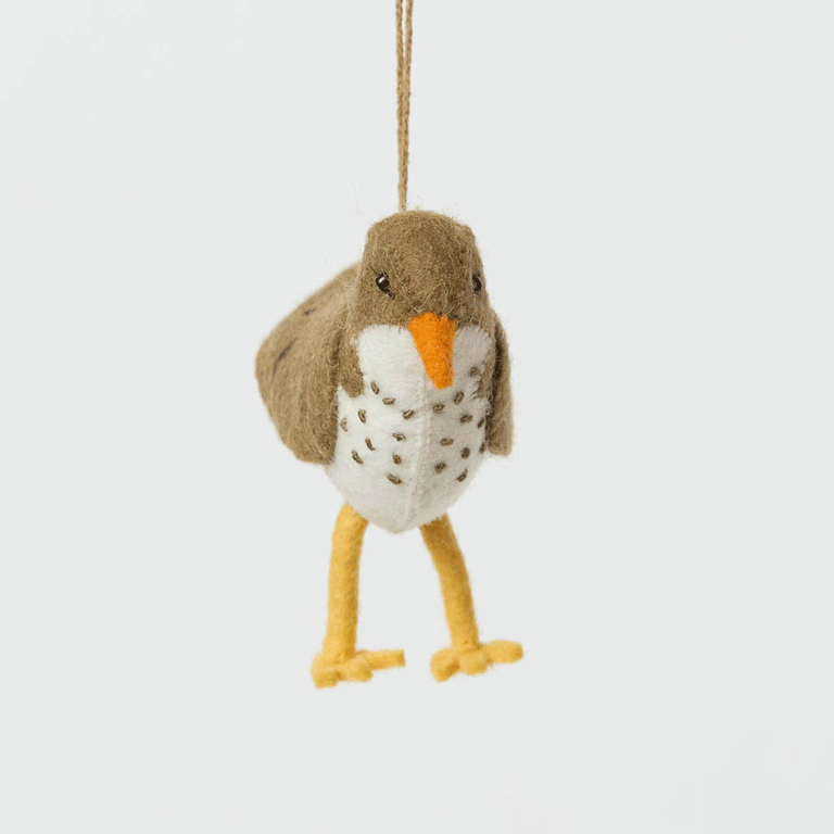 Bring a touch of the shoreline to your holiday décor with our delightful Spotted Sandpiper Ornament. Carefully handcrafted from eco-friendly wool felt, this charming bird captures the distinctive features of the beloved sandpiper, from its warm brown plumage and bright orange beak to its delicate spotted breast.
