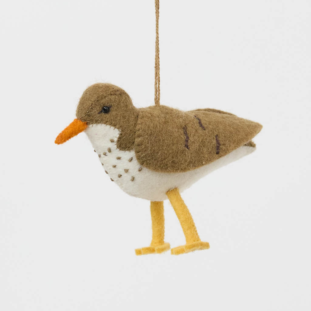 Bring a touch of the shoreline to your holiday décor with our delightful Spotted Sandpiper Ornament. Carefully handcrafted from eco-friendly wool felt, this charming bird captures the distinctive features of the beloved sandpiper, from its warm brown plumage and bright orange beak to its delicate spotted breast.