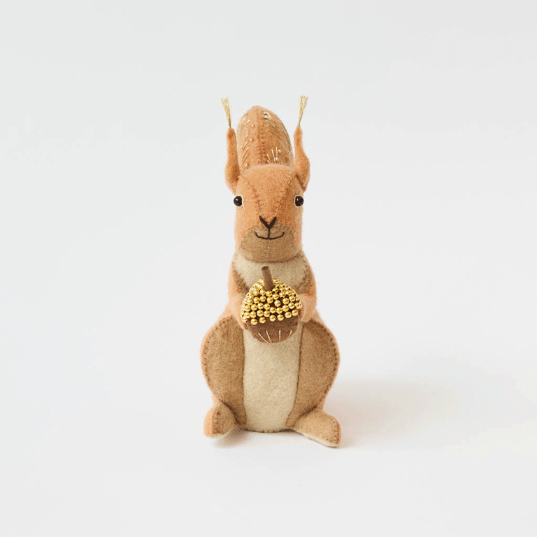 Our Squirrel Tree Topper is a handmade wool felt Christmas decoration featuring a beautifully embroidered bushy tail and golden beaded acorn, designed to perch atop your holiday tree or stand on its own as whimsical woodland décor.