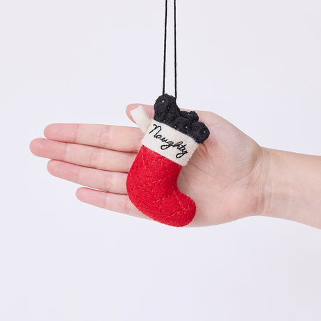 Craftspring’s Naughty Stocking with Coal Ornament held in hand to show its size — felt red stocking filled with felt coal and beads, embroidered with “naughty,” a charming heirloom-quality piece for Christmas gifting — ethically crafted by artisans using sustainable wool.