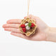 Felt ornament shaped like a stack of strawberry waffles, topped with three red strawberries, a swirl of white whipped cream, and a brown drizzle resembling Nutella. Handmade from soft wool felt with detailed embroidery, measuring approximately 2.5 inches tall and 1.5 inches wide, and comes with a hanging string. Held in a hand for scale