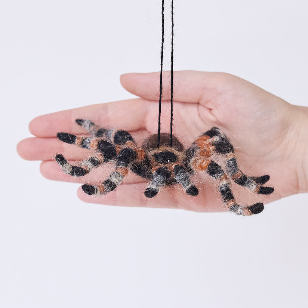 Craftspring’s Tarantula Ornament held in hand, showing its needle-felted body and hairy legs—an heirloom-quality holiday ornament, ethically crafted by artisans using sustainable wool.