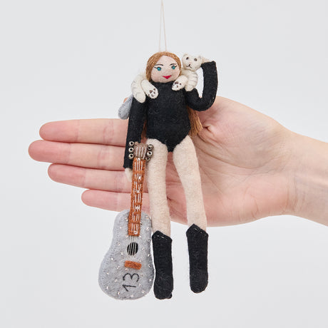 Craftspring’s Taylor Swift with Cat ornament held in front of a hand to show its size—handmade from sustainable wool with Taylor holding a guitar with the number 13 and a cat around her shoulders, ethically crafted by artisans using sustainable wool.