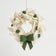 A handcrafted white holiday wreath ornament with green berries and a green bow, ready to hang.