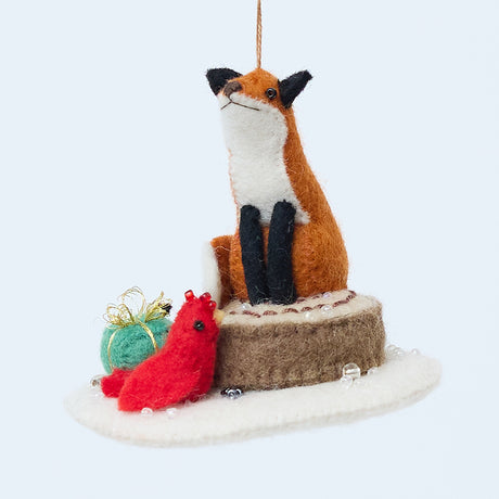 Handmade felt Fox on Stump Ornament from Craftspring, featuring a fox perched on a stump with a green present and red cardinal—heirloom-quality Christmas decor, perfect for holiday gifting, ethically crafted by artisans using sustainable wool.