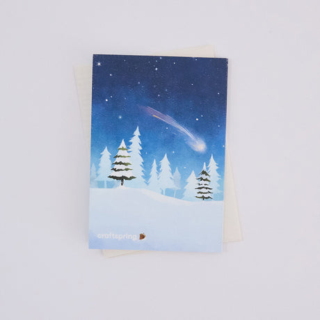 Back of Craftspring’s Woodland Tree Greeting Card, showing a snowy forest with a shooting star illustration, ethically printed in the USA on natural textured paper, perfect for sharing holiday cheer and gifting.