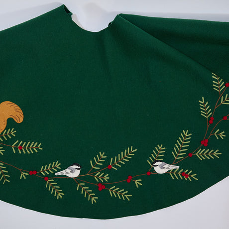 Craftspring’s Woodland Tree Skirt — handmade felt Christmas tree skirt with embroidered and appliqué pine branches and red berries, featuring woodland animals including a cardinal, squirrel, and chickadees — heirloom-quality holiday decor, ethically crafted by artisans using sustainable wool.