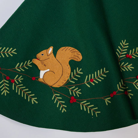 Close-up of Craftspring’s Woodland Tree Skirt showing an embroidered and appliqué squirrel nestled among pine branches and berries — festive holiday detail, handmade by artisans using sustainable wool.