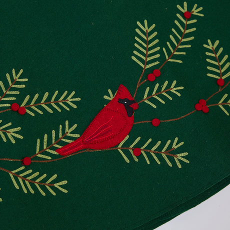 Close-up of Craftspring’s Woodland Tree Skirt showing an embroidered and appliqué red cardinal perched among pine branches and berries — delicate holiday design, handmade by artisans using sustainable wool.
