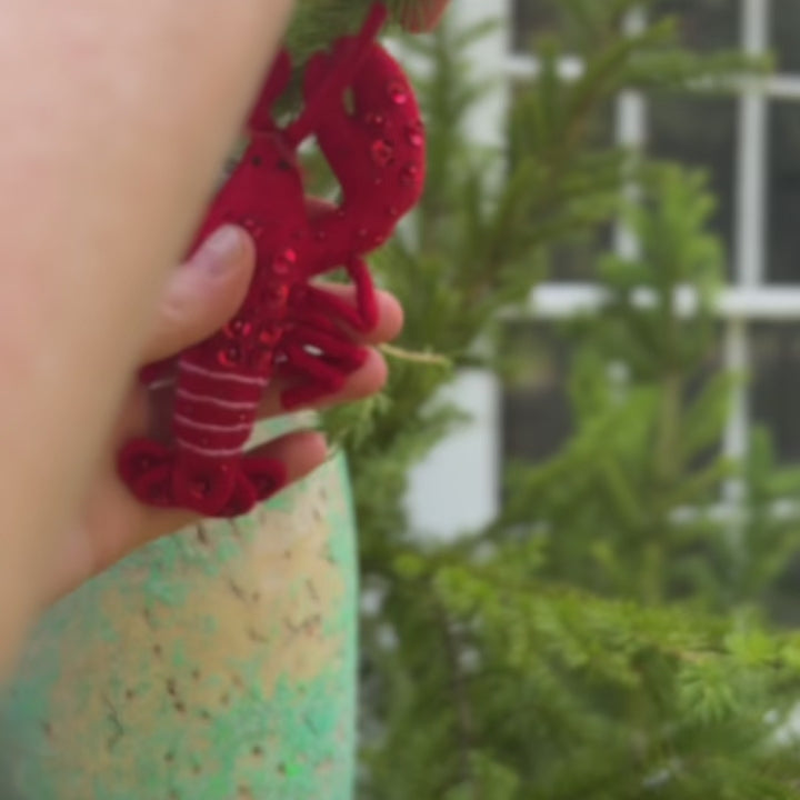 Commemorate the bounty of the northeastern seaboard with our handcrafted Bejeweled Red Lobster Ornament, designed to bring the spirit of coastal Maine to your home. Crafted from vibrant red felt and embellished with sparkling beads and sequins, this festive lobster ornament catches the light beautifully, adding texture, shimmer, and whimsical seaside charm to your holiday décor.