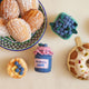 Hand-felted blueberry jam jar ornament with a gingham-style lid and a bunch of plump felt blueberries on top.  Alongside brunch favorites, both real and made of felt like pancakes and a pint of blueberries. Made from merino-blend wool, this 3-inch tall ornament is a charming, summer-inspired gift for bakers and brunch lovers. Perfect for cottagecore décor, holiday trees, or breakfast-themed bundles.