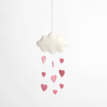 A handmade felt white cloud ornament snowing down three strings of pink hearts