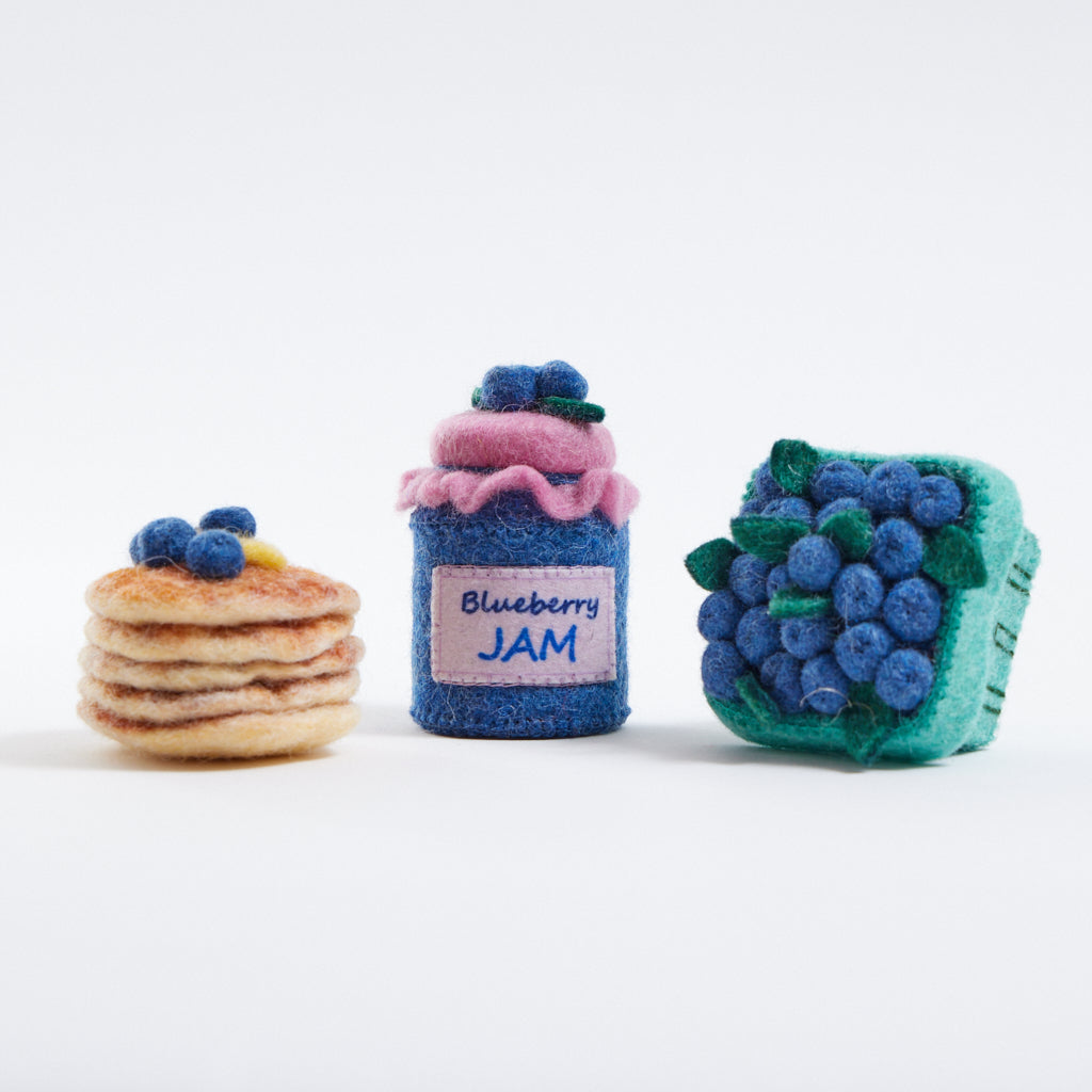 Blueberry-themed felt ornament gift set in a kraft box with crinkle paper. Includes a felt blueberry jam jar, blueberry pint basket, and blueberry pancake stack. Handmade from wool felt using traditional needle-felting. Fair trade and ready to hang.