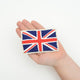 Felt British flag ornament featuring the embroidered Union Jack in red, white, and blue. Handmade from wool felt and cotton thread using traditional techniques. Fair trade and ready to hang. Held in a hand for scale.