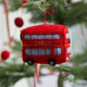 Felt ornament of a red London tour bus with holiday details, perfect for Christmas décor or travel-themed gifting. Handmade from wool felt. Fair trade and ready to hang On a christmas tree