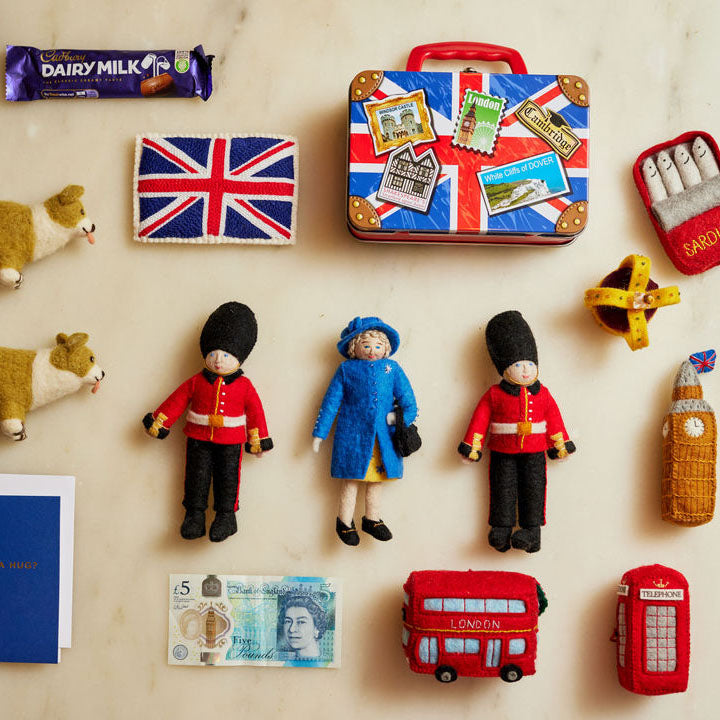 Queen Elizabeth II felt ornament wearing royal blue coat and hat, with black handbag and detailed embroidery. Handmade wool Christmas ornament honoring British royalty. Fair trade and ready to hang. Along with Queens guards, Union Jack flags and corgis out of felt.