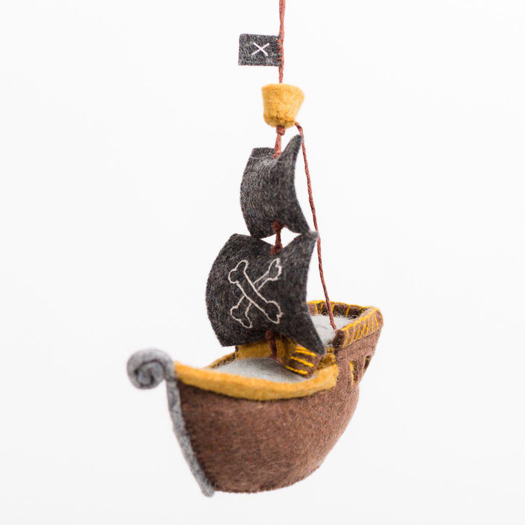 A handmade felt pirate ship ornament with a brown hull and black sails.