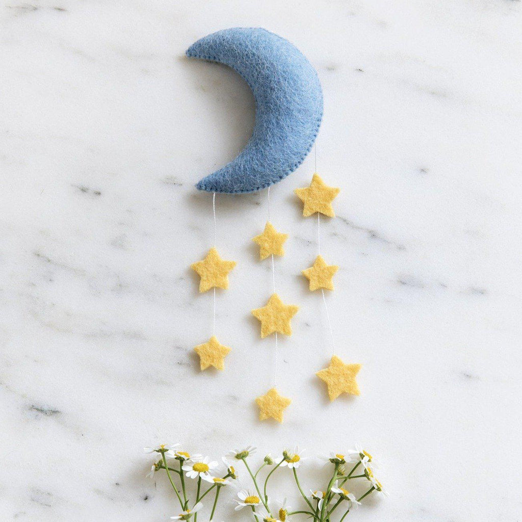 A Craftspring handmade blue felt crescent moon ornament with strings of yellow stars
