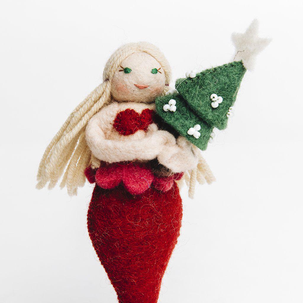 A Craftspring handmade felt mermaid ornament with long blond hair a red tail and bikini top holding a small christmas tree 