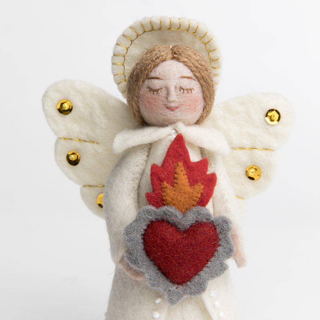 A craftspring handmade felt angel ornament wearing white robes, a halo, sequined wings and holding a flaming heart