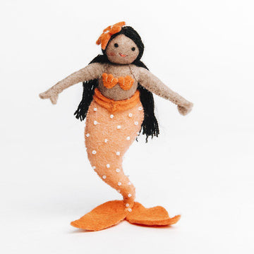A Craftspring handmade felt sunrise mermaid ornament with long black hair brown skin and an orange beaded tail and seashell top